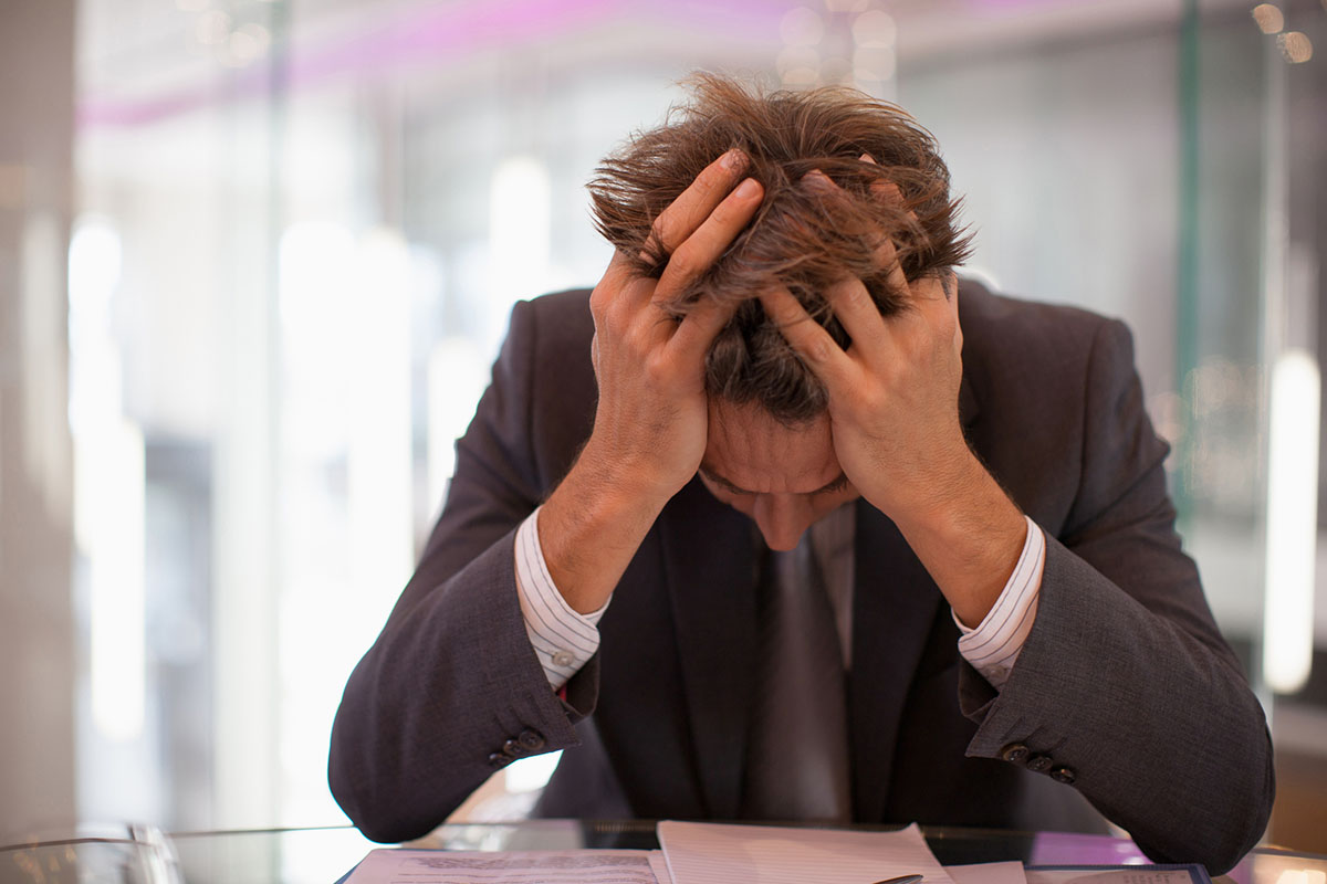 Frustrated businessman sitting at desk with head in hands